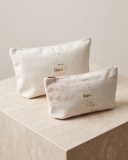 Pochette Blanc in lino bianco con piccoli dettagli bordeaux su un piano in pietra